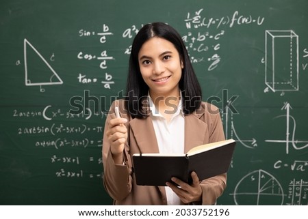 Young asian teacher woman teaching holding book and video conference with student looking camera. Female teacher training the mathematics in classroom blackboard from online course.