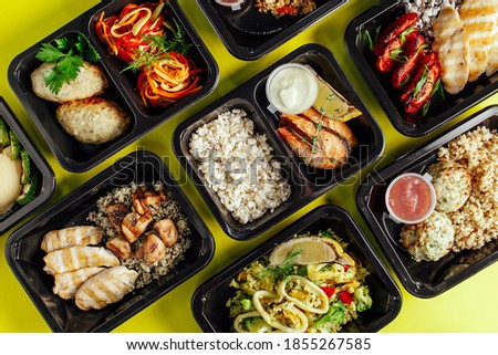 Healthy lunch at the workplace. Pick up food in black containers with Cutlery on a yellow background