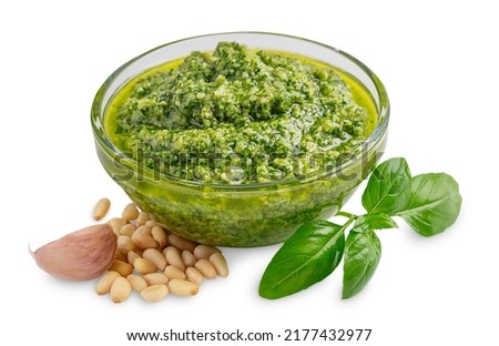 Homemade fresh herbal italian pesto sauce made of blended raw green basil leaves, pine nuts, garlic, parmesan and olive oil served in glass bowl isolated on white background used for pasta or salad Foto d'archivio © 