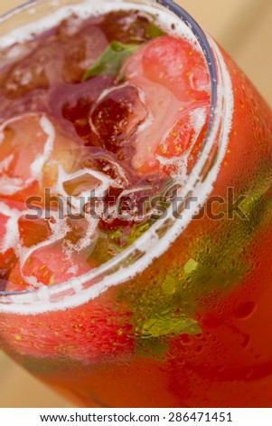 Cold lemonade with strawberries, mint and ice on the outdoor veranda summer day, sunlit.