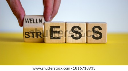 Wellness instead of stress. Hand turns a cube and changes the word 'stress' to 'wellness'. Beautiful yellow table, white background. Concept. Copy space. Stock foto © 