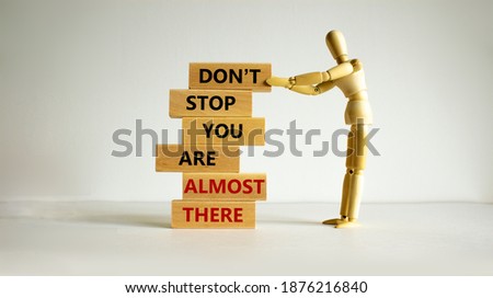 You are almost there symbol. Wooden blocks with words 'dont stop you are almost there'. Wooden model of human. Beautiful white background, copy space. Business and almost there concept. 商業照片 © 