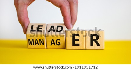 Manager versus leader symbol. Businessman flips wooden cubes and changes the word 'manager' to 'leader'. Beautiful white background, copy space. Business and manager versus leader concept.