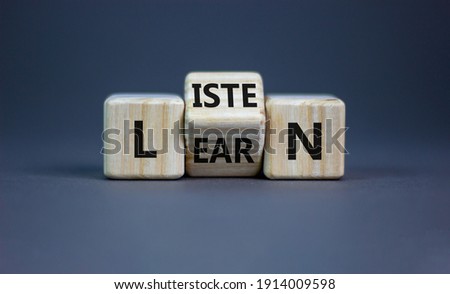 Listen and learn symbol. Turned a wooden cube and changed the word 'listen' to 'learn'. Beautiful grey background, copy space. Business, education and listen and learn concept.