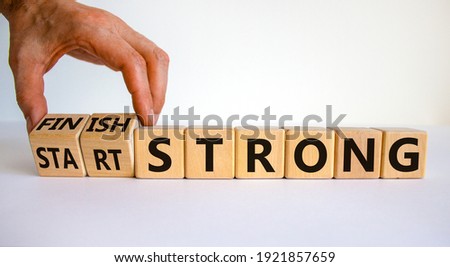 Start and finish strong symbol. Businessman turns wooden cubes, changes words 'start strong' to 'finish strong'. Beautiful white background, copy space. Business and start and finish strong concept.