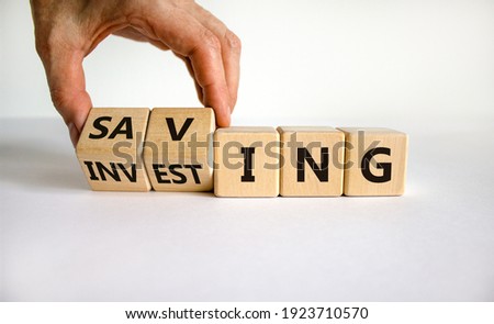 Saving or investing symbol. Businessman turns cubes and changes the word 'investing' to 'saving'. Beautiful white table, white background, copy space. Business and saving or investing concept. Stock foto © 