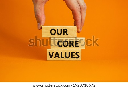 Our core values symbol. Concept words 'Our core values' on wooden blocks on a beautiful orange background, businessman hand. Business and our core values concept. Copy space.