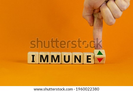 Corona immune and medical symbol. Doctor turns a cube and changes the expression 'immune down' to 'immune up'. Beautiful orange background. Medical, immune level concept. Copy space.