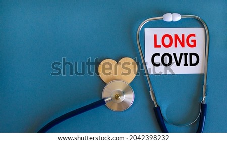 COVID-19 pandemic long covid symbol. White card with words long covid, beautiful blue background, wooden heart and stethoscope. Medical, COVID-19 pandemic long covid concept.