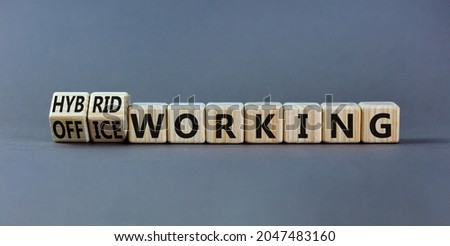 Hybrid or office working symbol. Turned wooden cubes and changed words 'office working' to 'hybrid working'. Beautiful grey background. Business, hybrid or office working concept, copy space.