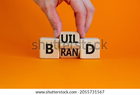 Build your brand symbol. Businessman turns wooden cubes and changes the word 'build' to 'brand'. Beautiful orange background. Build your brand and business concept. Copy space.