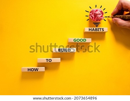 Build good habits symbol. Wooden blocks on beautiful yellowbackground, copy space. Words 'How to build good habits'. Businessman hand, light bulb. Build good habits concept. Copy space.