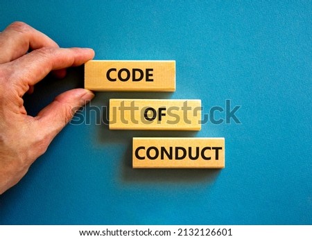 Code of conduct symbol. Concept words Code of conduct on wooden blocks on a beautiful blue table blue background. Businessman hand. Business and code of conduct concept. Copy space. Сток-фото © 