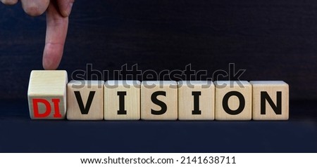 Division or vision symbol. Turned cubes and changed the concept word Division to Vision. Businessman hand. Beautiful grey table grey background. Business division or vision concept. Copy space. Stockfoto © 