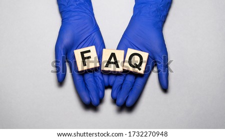 Q & A FAQ Questions and answers on wooden cube blocks in female hands in dark blue gloves over grey blue table Stock foto © 