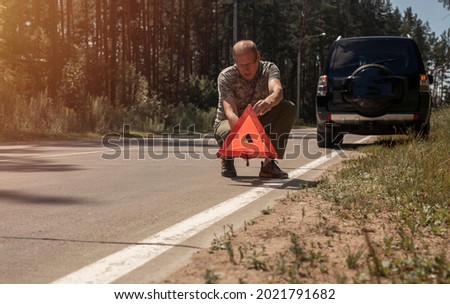 Foto Bild Fahrer stellt rotes Dreieck in der Nähe des kaputten Autos auf