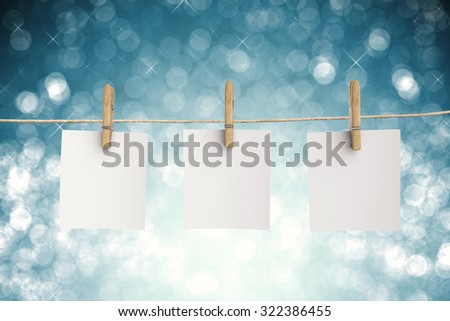 clothespin hanging with blank paper on blue glitter background