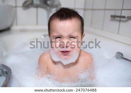 child bathing  with foam bath and makes faces
