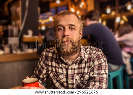 brave, handsome bearded hipster blonde holding a metal cup of warm mulled wine.