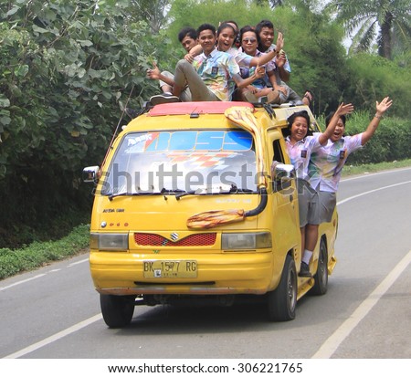 MEDAN, INDONESIA - APRIL 15, 2015: students are going to celebrate of finishing of school and moving to tourist place in the van - someone even on the roof of van