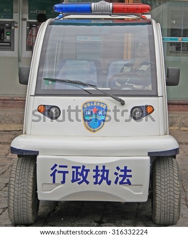 LIJIANG, CHINA - JUNE 10, 2015: police officer is sitting inside police car on the street in Lijiang, China