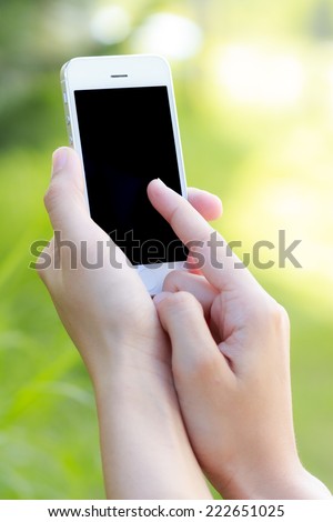 Hands using smart phone in green field