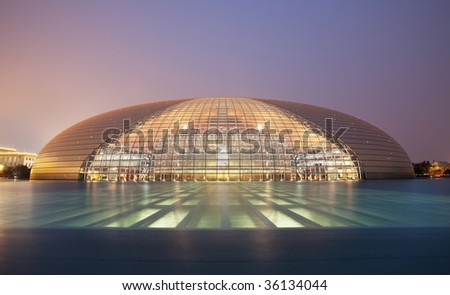 Frontal view of Beijing National Grand Theater shot with water reflections against a clear blue night sky.