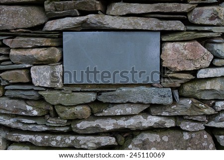 A blank plaque/sign on a stone wall in the Lake District, UK.