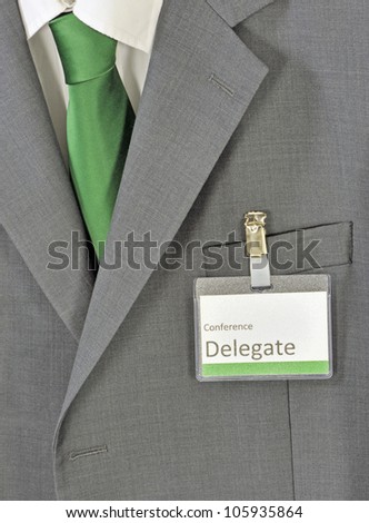 Closeup on male gray business suit, green tie and conference delegate badge