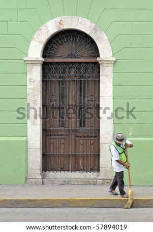 Mexican man sweeping street in front of old colonial building in Mexico