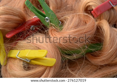 Long blond hair twisted in curls fastened with yellow, red and green clothespin