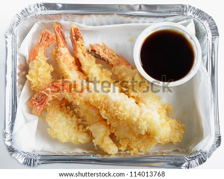 A fast-food carry-out of prawn tempura, known as shrimp tempura in the US, in an aluminium tray with a a pot of soy sauce.