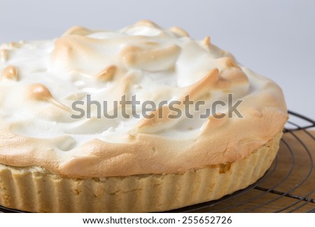 Homemade lemon meringue pie, a classic of European dessert cuisine, on a cooling rack fresh from the oven