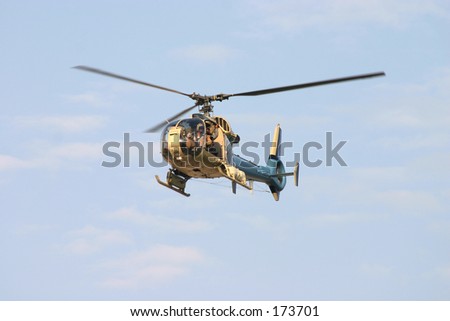 A civilian helicopter in flight with a crew member filming events below.