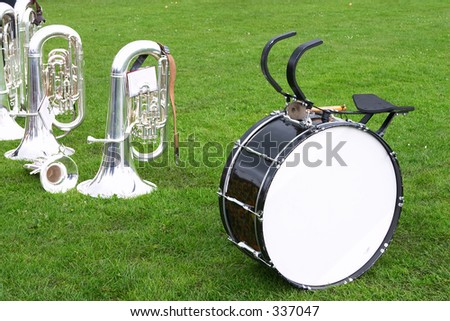 Tubas, bass drum and a cornet or trumpet on the grass as a brass band takes a break during a village fair.