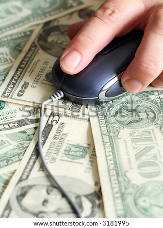 Fingers controlling a mouse over an array of US currency bills, symbolic of earning money through the internet or by using computers in some way.