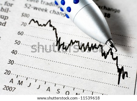 A biro on a newspaper\'s graph of a falling stock price. Large depth of field.