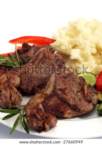 A meal of grilled lamb chops, mashed potato and tomato and cucumber salad