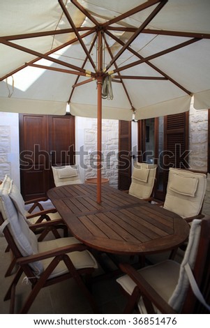 A wooden table and chairs on a patio in a Greek holiday villa