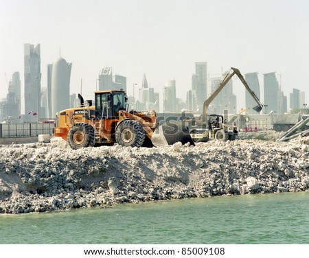 DOHA, QATAR - APRIL 26: Heavy construction machinery at work on harbour alterations  with the city\'s high-rise skyline behind, in Doha Bay,in Doha, Qatar on April 26 2011. Qatar is hotspot for construction activity.