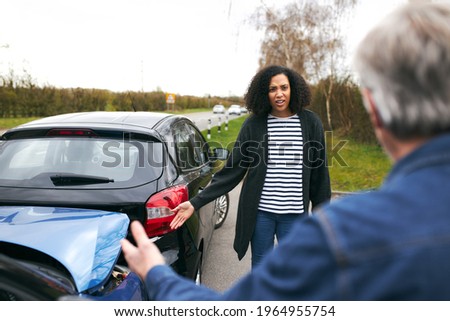 Senior male driver arguing over blame for car accident with a younger female motorist Сток-фото © 