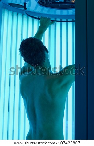 young man closeup at tanning solarium light on