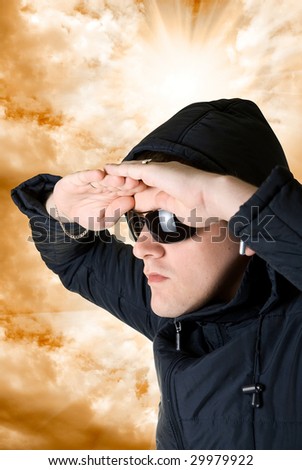 man look at distance in black sunglasses and jacket on orange sky background
