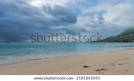 Rain clouds hung over the ocean. Several yachts on turquoise water. A green hill against the sky. Sandy beach in the foreground. Seychelles. Mahe.  Beau Vallon Photo stock © 