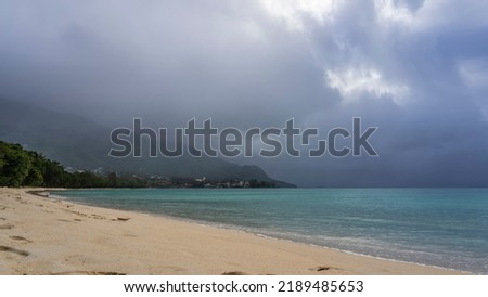A foggy day on a tropical island. The turquoise ocean is calm. Footprints on a sandy beach. The mountain is hidden in low clouds. Seychelles. Mahe. Beau Vallon Photo stock © 