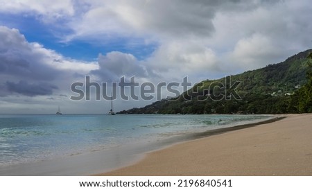 Sandy beach on a tropical island. The turquoise ocean is calm. Yachts are visible in the distance. A green hill against a background of blue sky and clouds. Seychelles. Mahe. Beau Vallon Photo stock © 