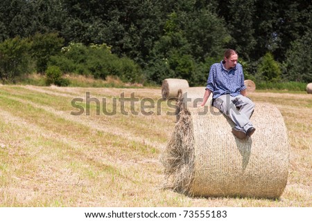 Young man sitting on a roll of hay