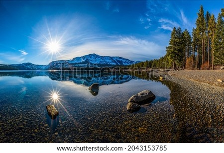 Bright sun over a mountain lake. Lake water reflection. Beautiful lake view. Lake in mountain forest