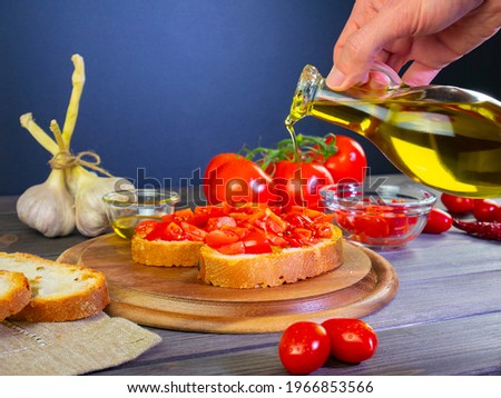 Pour olive oil on the food. Mediterranean food, Italian bruschetta with ingredients: bread, tomato, garlic and olive oil. Still life food. Hand holds bottle of extra virgin olive oil. ストックフォト © 