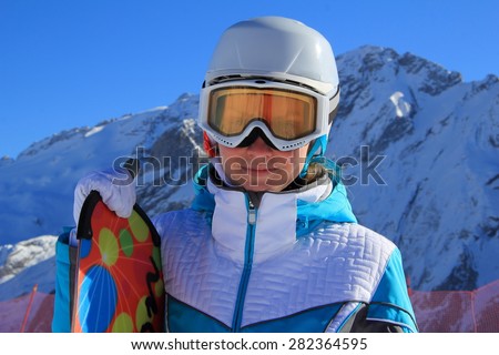 young beautiful girl in a blue ski suit and white hat on his head on a background of mountains